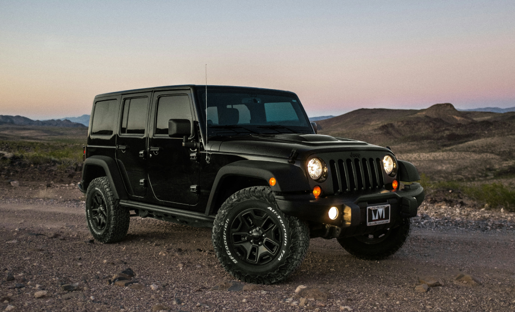 A black jeep parked on top of a dirt hill.